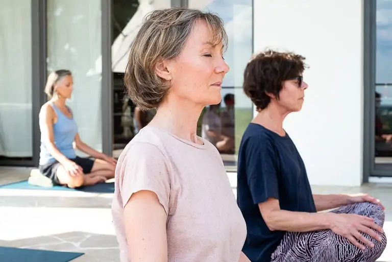 Trois personnes méditant pendant un cours de Yoga à Mauves sur Loire..